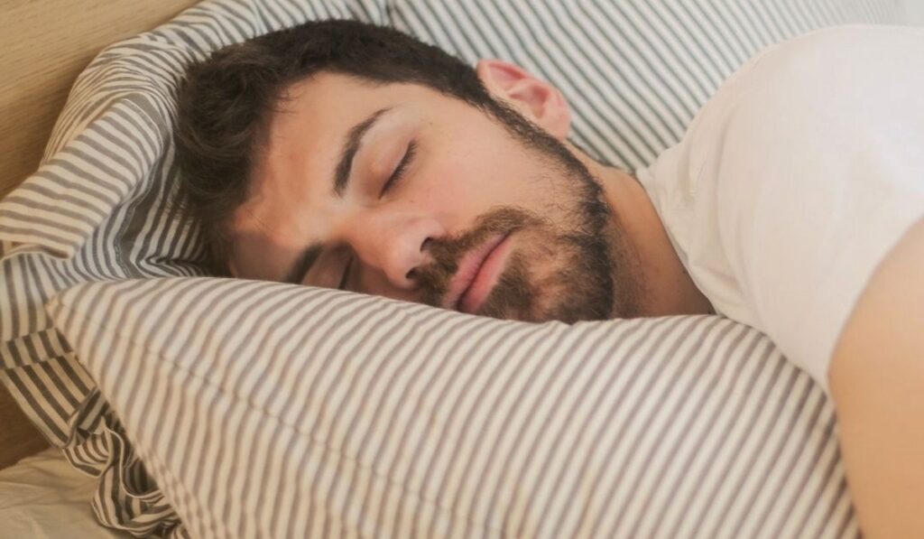Man sleeping on striped pillow in bed